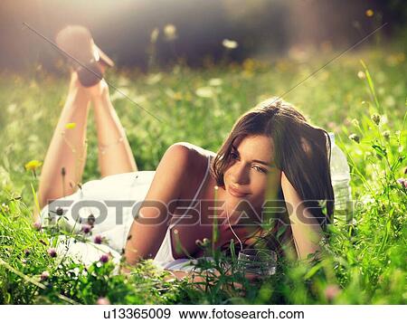 Young woman lying in meadow, leaning on elbow View Large Photo Image Stock Photo - Young woman lying in meadow, leaning on elbow. Fotosearch