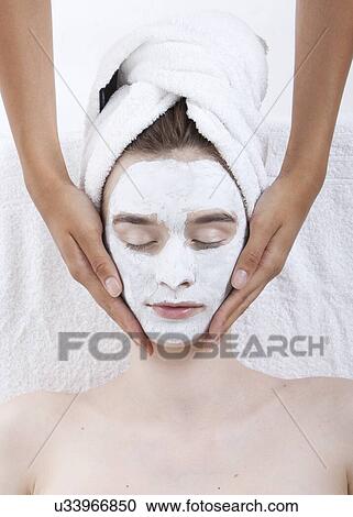 Stock Image - Young woman receiving facial treatment at spa. Fotosearch