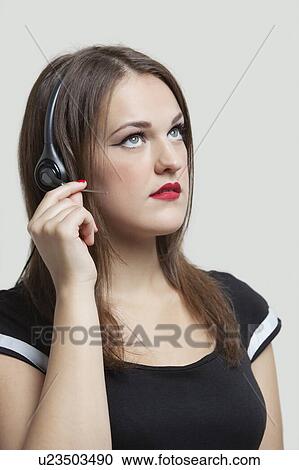 Stock Image - Young woman wearing headphones over gray background. Fotosearch