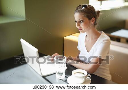 Young woman working on laptop at cafe View Large Photo Image Stock Photo - Young woman working on laptop at cafe. Fotosearch