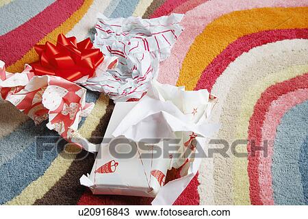 Stock Image - Used wrapping paper on rug (high angle view). Fotosearch