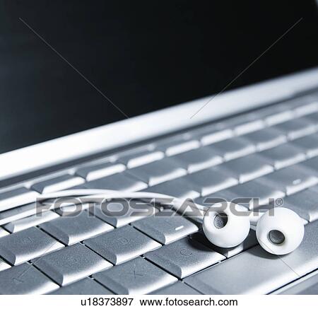 Stock Photo - Earphones on Computer Keyboard. Fotosearch