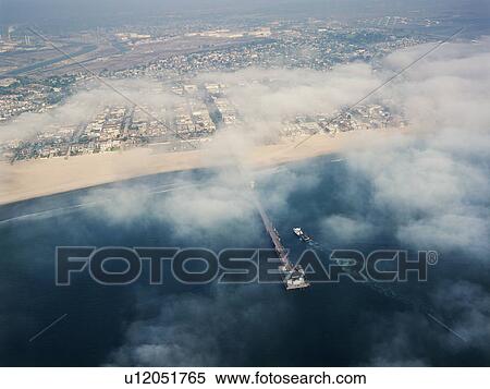 Stock Photography - Aerial view of clouds covering beachfront and fishing pier in southern California. Fotosearch