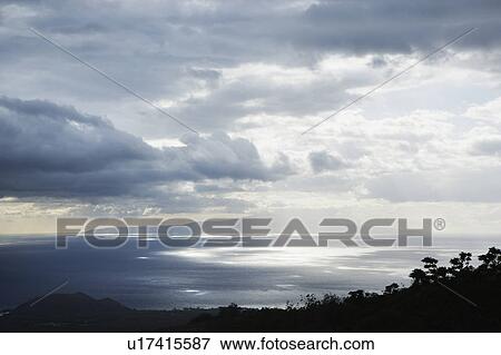 Stock Photo - View of island in Pacific ocean with clouds from Maui, Hawaii. Fotosearch