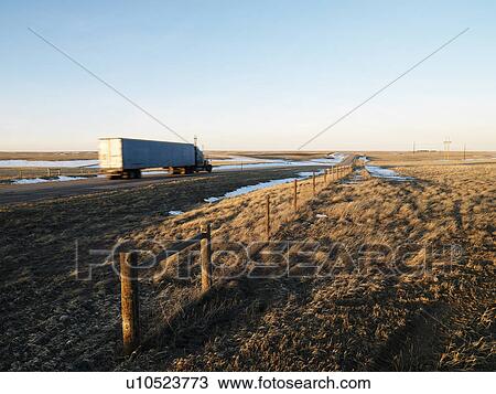 Stock Image - Transfer truck driving through rural setting.. Fotosearch