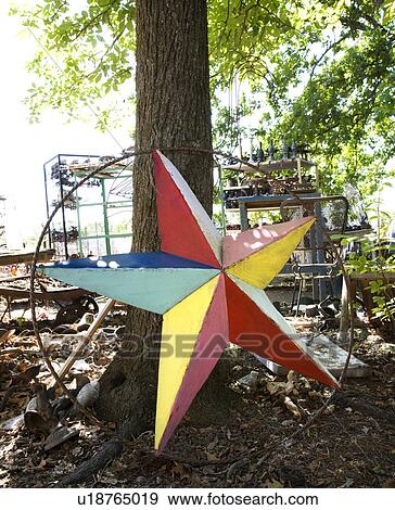 Stock Photo - Colorful painted star made of metal leaning against tree.. Fotosearch