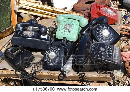 Stock Image - Stack of old broken rotary telephones on table.. Fotosearch