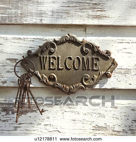 Stock Image - Welcome sign and metal keys on old white peeling building.. Fotosearch