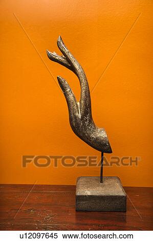 Stock Photography - Carved hand sculpture from Thailand against orange wall.. Fotosearch