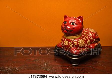 Picture - Chinese red cat statue against orange wall.. Fotosearch