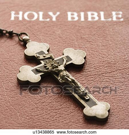 Stock Photography - Crucifix laying on cover of closed Holy Bible. Fotosearch