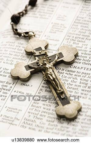 Stock Image - Crucifix on rosary lying on open Bible. Fotosearch