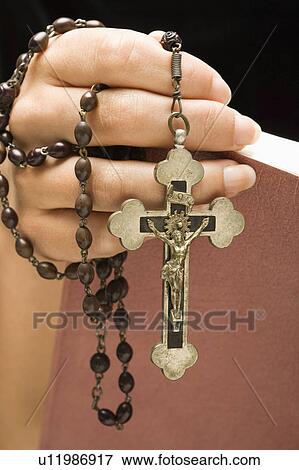 Holding Holy Bible open with rosary and crucifix in hand View Large Photo Image Stock Photo - Holding Holy Bible open with rosary and crucifix in hand. Fotosearch