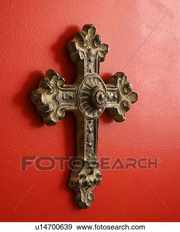 Stock Photo - Ornate religious cross hanging on red wall. Fotosearch