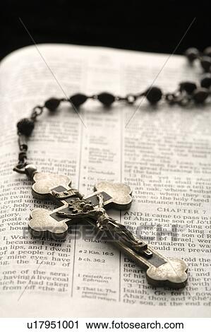 Stock Image - Rosary with crucifix lying on open Bible. Fotosearch