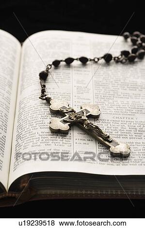 Rosary with crucifix lying on open Bible. View Large Photo Image Stock Photo - Rosary with crucifix lying on open Bible.. Fotosearch