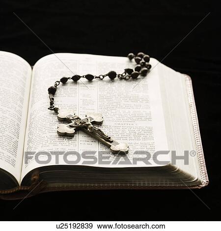 Rosary with crucifix lying on open Bible. View Large Photo Image Stock Photo - Rosary with crucifix lying on open Bible.. Fotosearch