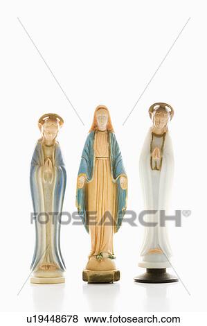 Stock Photo - Virgin Mary statue with hands held out with angelic figures on each side against white background.. Fotosearch