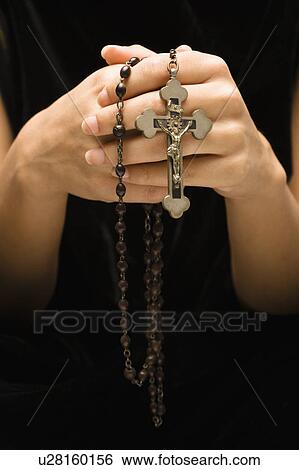 Stock Photograph - Woman holding rosary with crucifix.. Fotosearch