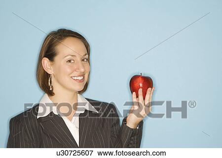 Businesswoman smiling holding red apple View Large Photo Image Stock Photo - Businesswoman smiling holding red apple. Fotosearch