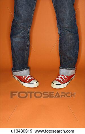 Stock Photo - Person in jeans and sneakers with feet turned inward. Fotosearch