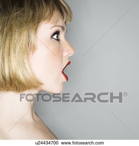 Stock Image - Profile portrait of young blonde woman who's mouth is open in shock.. Fotosearch