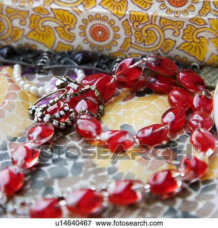 Stock Photo - Red bead necklace against pattern mosaic. Fotosearch