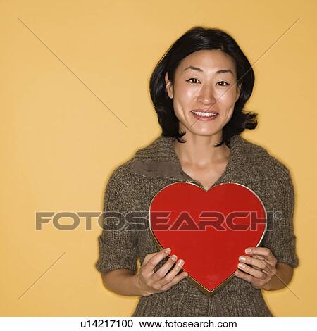Stock Image - Woman holding red heart shaped box. Fotosearch
