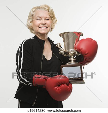 Woman wearing boxing gloves holding trophy View Large Photo Image Stock Image - Woman wearing boxing gloves holding trophy. Fotosearch