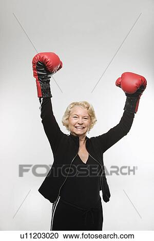 Woman wearing boxing gloves raised in the air View Large Photo Image Stock Image - Woman wearing boxing gloves raised in the air. Fotosearch