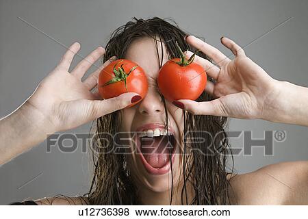 Stock Photo - Woman with tomatoes covering her eyes. Fotosearch