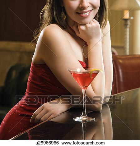 Adult woman in red dress smiling and standing at bar with drink. View Large Photo Image Stock Photograph - Adult woman in red dress smiling and standing at bar with drink.. Fotosearch