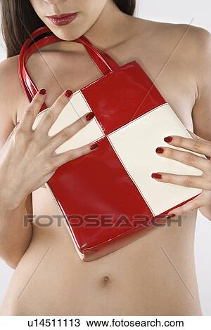 Stock Image - Topless woman holding purse to her chest.. Fotosearch