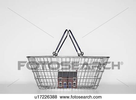Stock Photo - A model of a red bricked house in a shopping basket.. Fotosearch