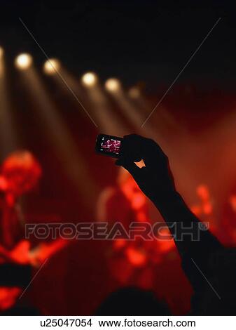 Picture - Cell phone taking picture of a concert.. Fotosearch