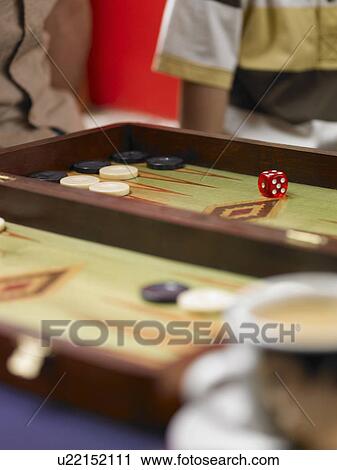 Stock Image - Family playing backgammon, focus on board and dice, close-up. Fotosearch