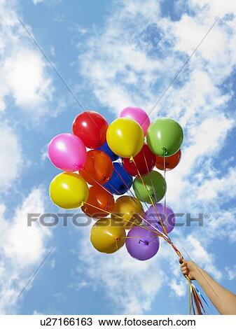 Stock Image - Hand holding colorful balloons. Fotosearch