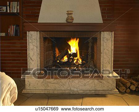 Stock Photo - Log fire burning in fireplace in living room. Fotosearch