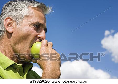 Stock Image - Man biting into apple. Fotosearch