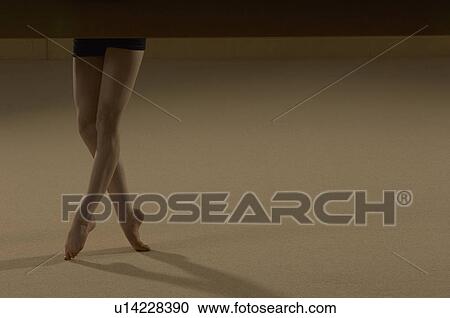 Stock Image - Teenage gymnast (16-18) balancing on toes, low section. Fotosearch