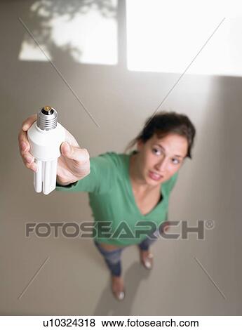 Stock Photo - Woman fixing a light bulb. Fotosearch