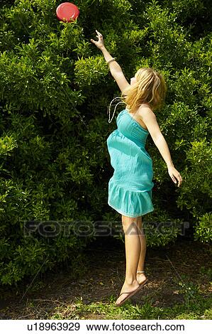 Stock Photo - Woman jumping to reach a frisbee. Fotosearch