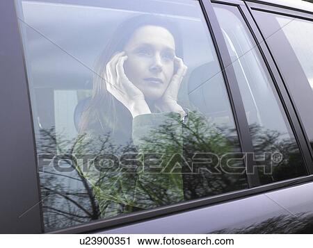 Stock Image - Woman looking through her car window. Fotosearch