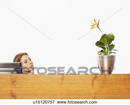 Stock Photo - Woman with a plant at a desk. Fotosearch