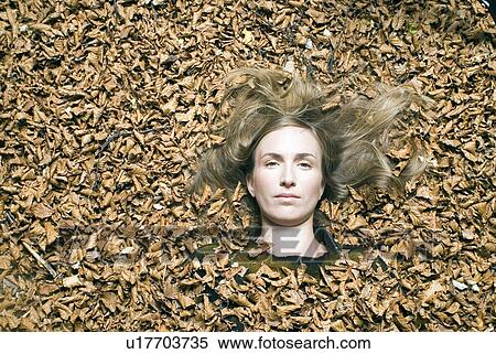Stock Photography - Young woman lying down on leafs.. Fotosearch