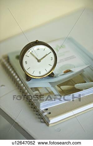 Stock Image - Antique clock and notebook on cabinet. Fotosearch