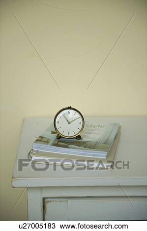 Stock Image - Antique clock and notebook on cabinet. Fotosearch