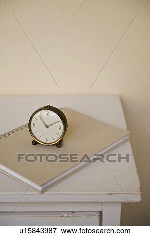 Stock Photo - Antique clock and notebook on cabinet. Fotosearch