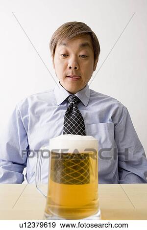 Stock Photo - Businessman looking at beer. Fotosearch
