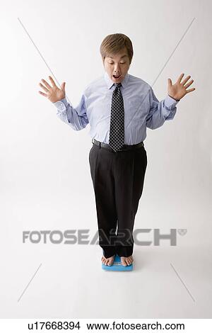 Businessman standing on bathroom scale View Large Photo Image Picture - Businessman standing on bathroom scale. Fotosearch